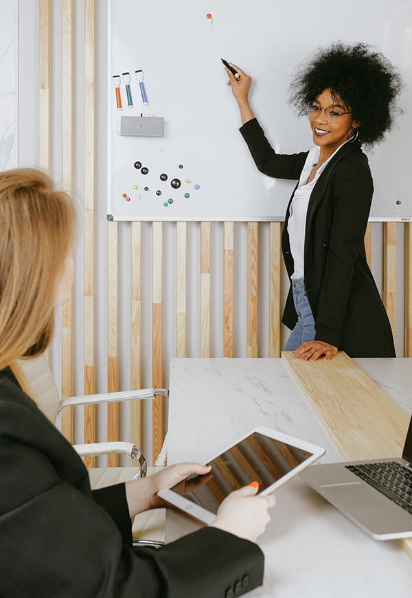 Une femme fait une présentation devant un tableau blanc dans un milieu professionnel